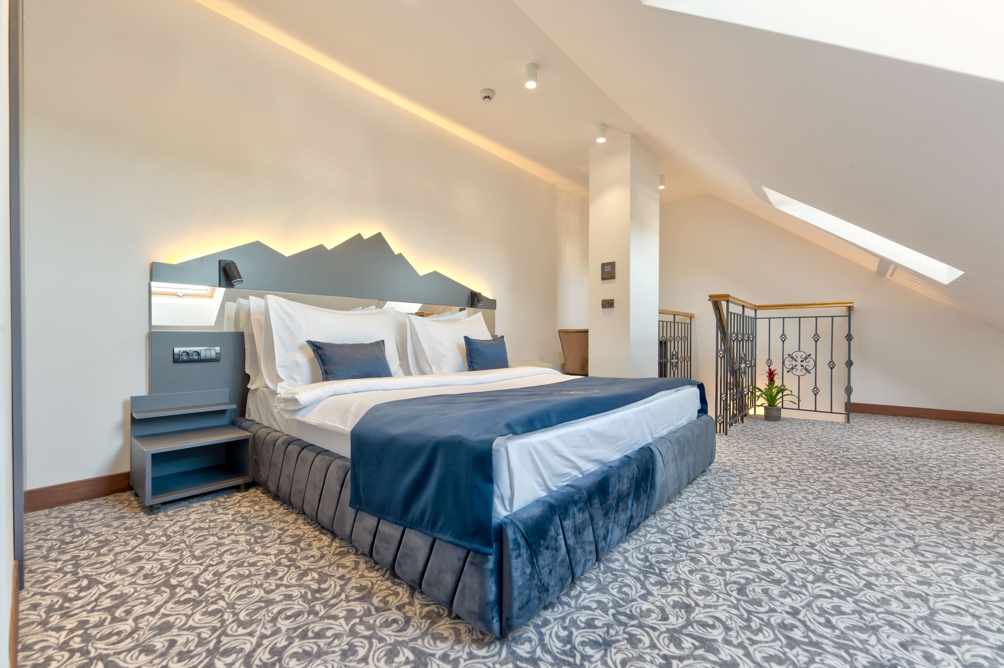 Un dormitorio moderno con una cama, mesitas de noche y un tragaluz.