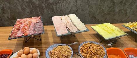Un bufé con diversos alimentos, incluyendo carnes, huevos y cereales.