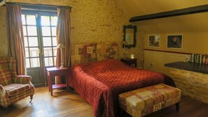 Une chambre confortable avec un grand lit, une chaise, un banc et une commode.