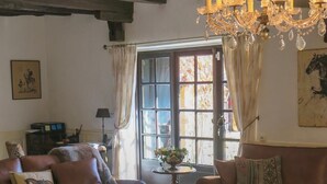 Un salon chaleureux avec des canapés en cuir, une table basse en bois, un lustre et une grande fenêtre agrémentée de rideaux.