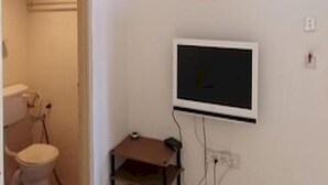 A small room with a television mounted on the wall, a door leading to a bathroom, and a small piece of artwork above the TV.