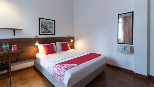Ein ordentlich eingerichtetes Hotelzimmer mit Bett, Nachttisch und Stuhl.