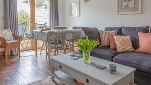 Ett vardagsrum med en soffa, fåtöljer, ett soffbord och en matplats med ett bord och stolar.