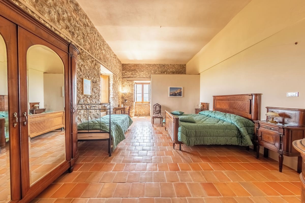 Un dormitorio con pared de piedra, muebles de madera y suelo de baldosas.