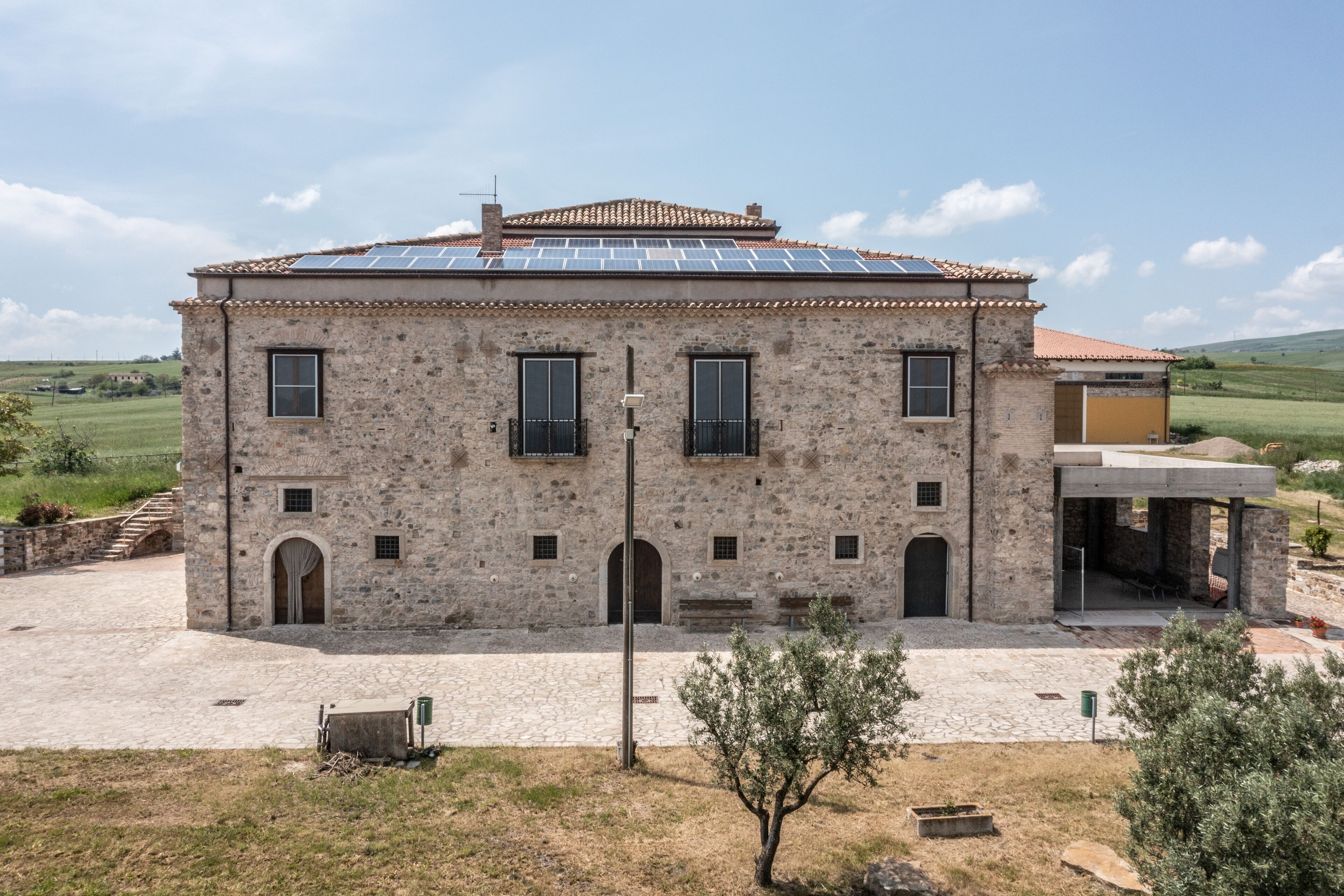 A stone building with a tiled roof, solar panels, and a courtyard.