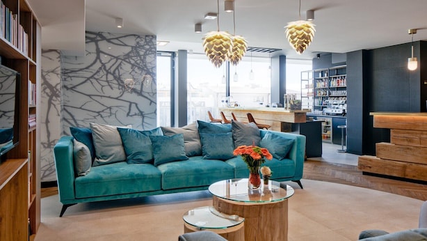 A modern living area with a teal sofa, a glass coffee table, and a bookshelf. - B&B HOTEL Tomaszów Lubelski (Tomaszow Lubelski)