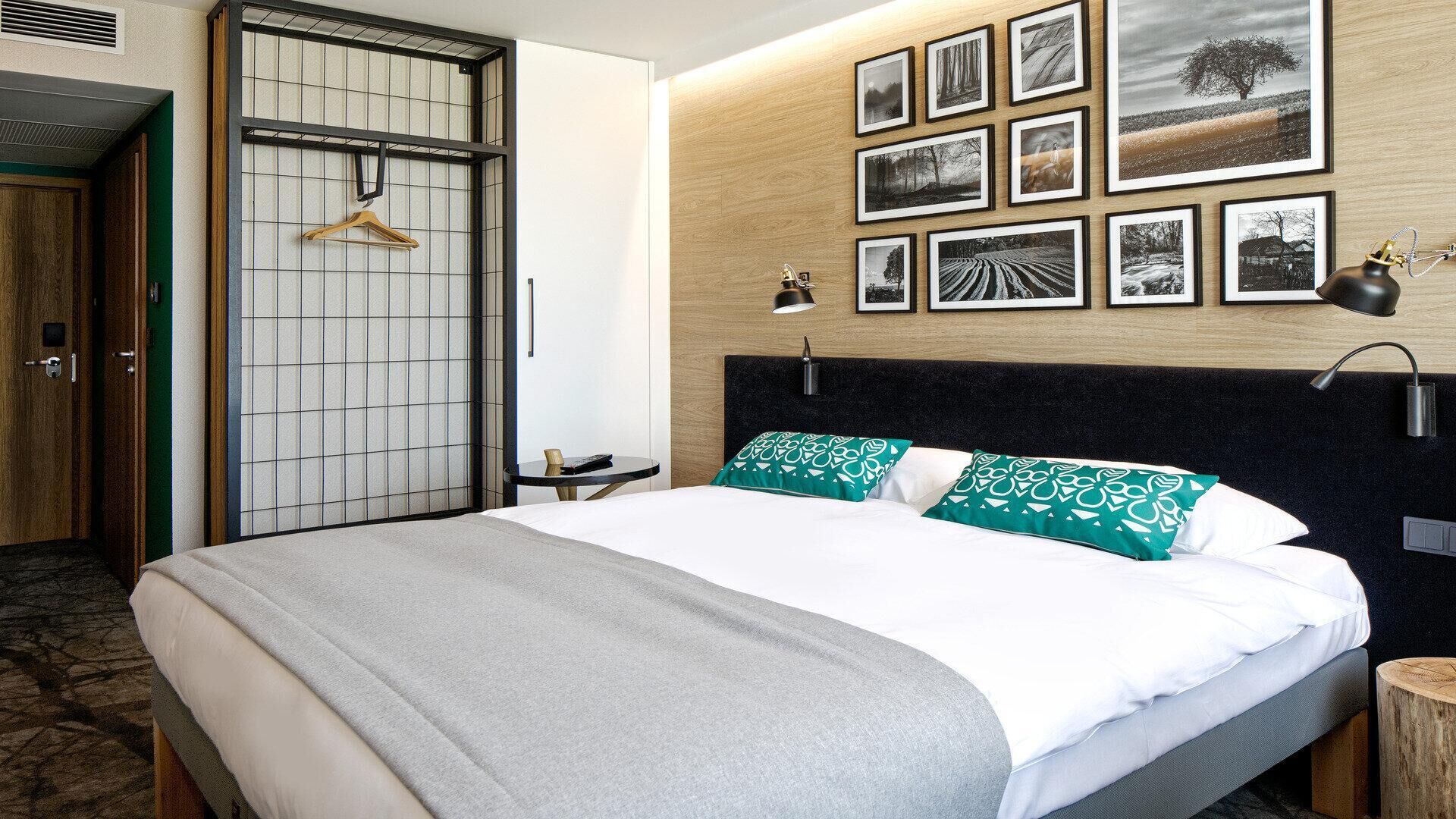 A hotel room with a bed, a wooden headboard, a wall-mounted picture gallery, and a traditional Japanese shoji screen door.