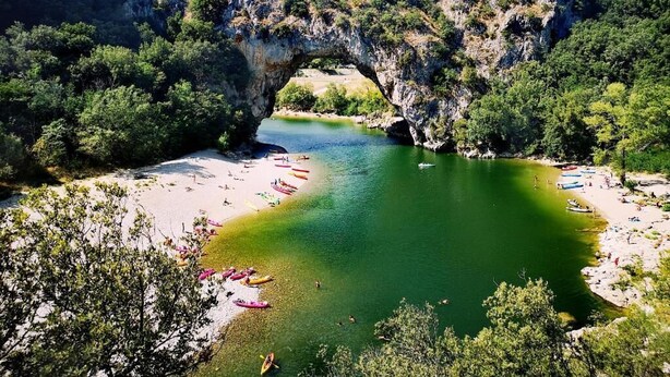 A natural arch over a river with a beach and boats. - Domaine de l'Astic  (Vagnas)