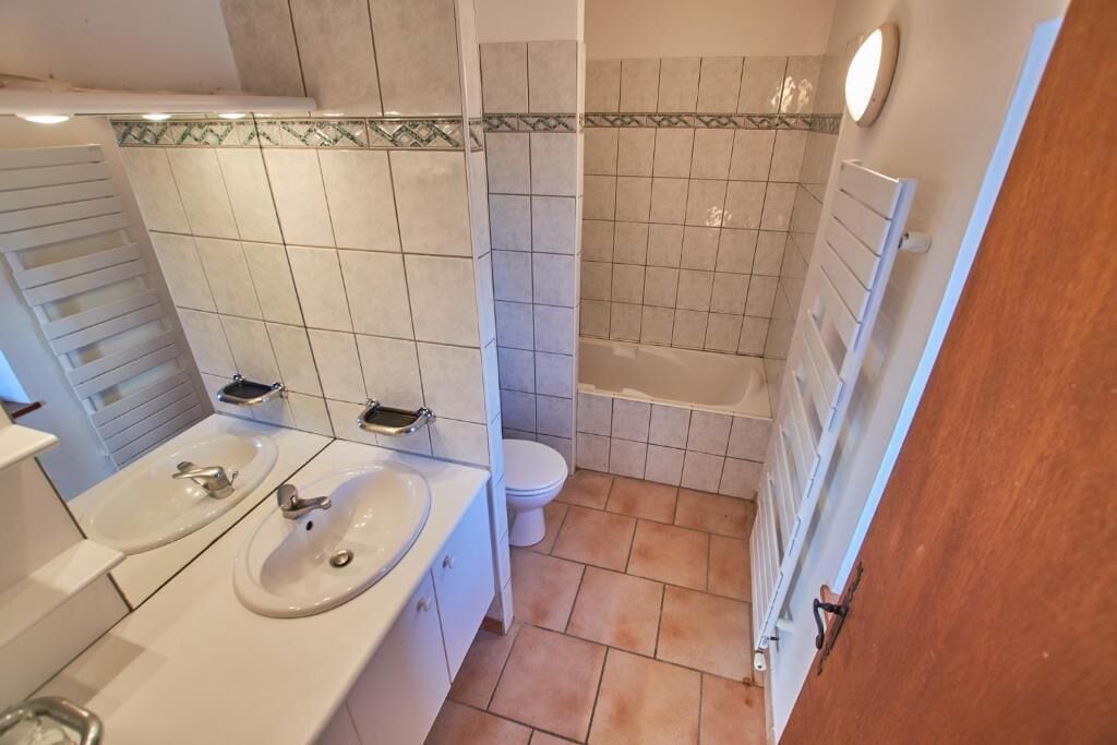 A bathroom with a double sink, toilet, and bathtub.