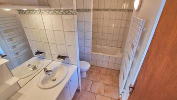 A bathroom with a double sink, toilet, and bathtub.