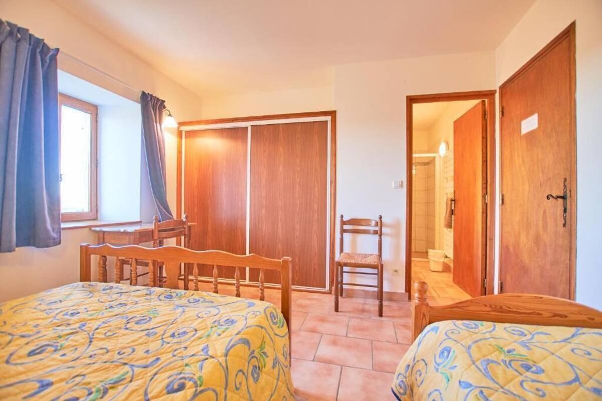 Een slaapkamer met twee bedden, een houten garderobe, een stoel en een raam met gordijnen.