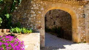 A stone archway leading to a building with a tiled roof. - Domaine de l'Astic  (Vagnas)
