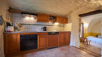 Una cocina con armarios de madera, lavavajillas y salpicadero de azulejos.