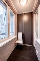 Un pasillo estrecho con una ventana, una silla y una puerta.