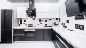 A modern kitchen with a built-in oven, a microwave, and a large flat-screen TV. - Apartment next to the shopping center (Minsk)