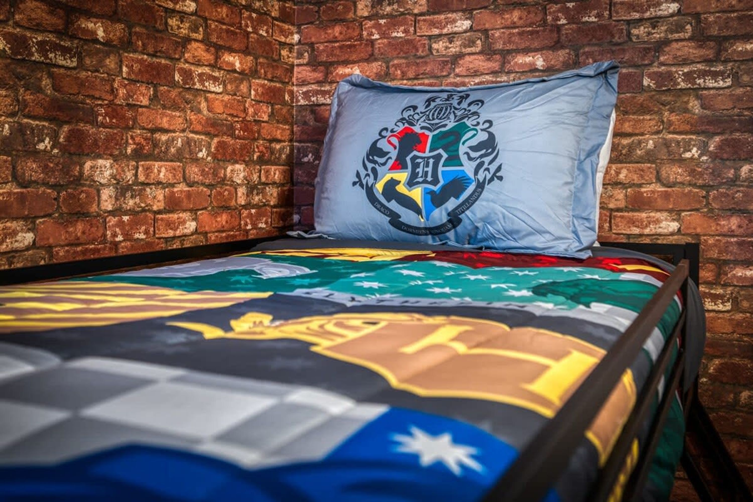 A bed with a colorful quilt and a pillow with a crest.