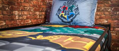 A bed with a colorful quilt and a pillow with a crest.
