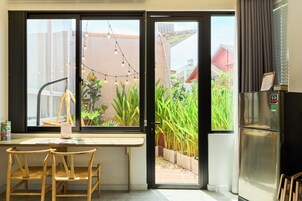 Una cocina con comedor, refrigerador y vista a un jardín a través de la puerta abierta.