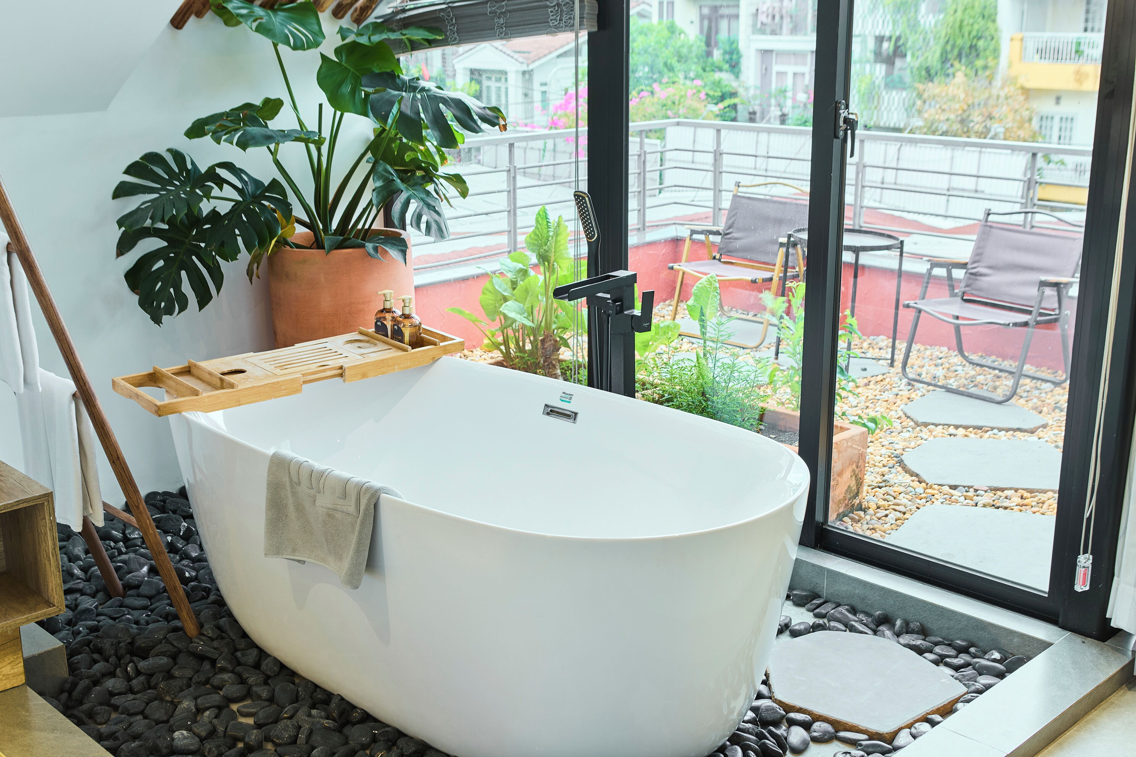 Een moderne badkamer met een vrijstaand bad, een houten plank en een potplant.