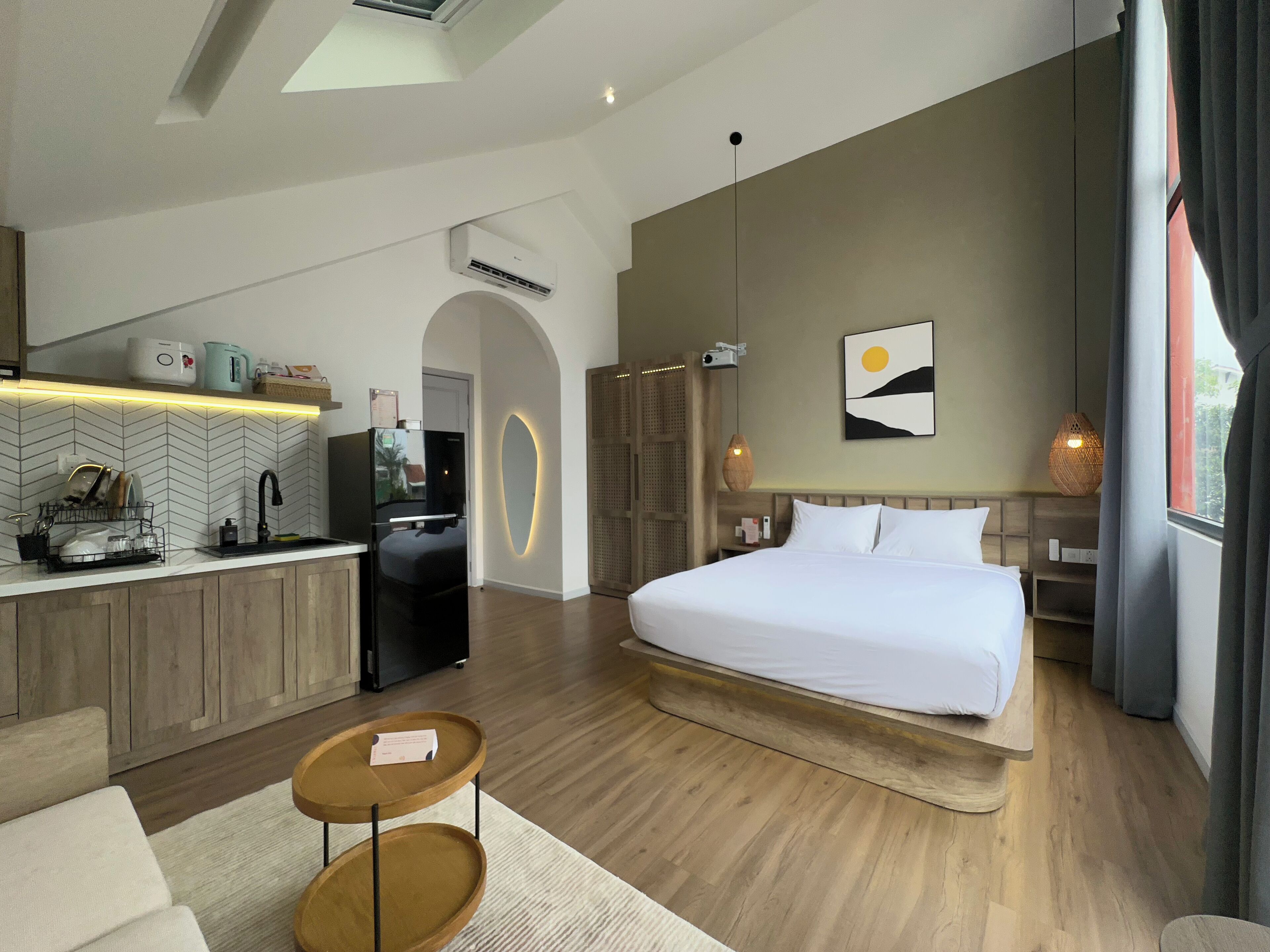 Una habitación de hotel moderna con kitchenette, una cama grande y vistas al exterior.
