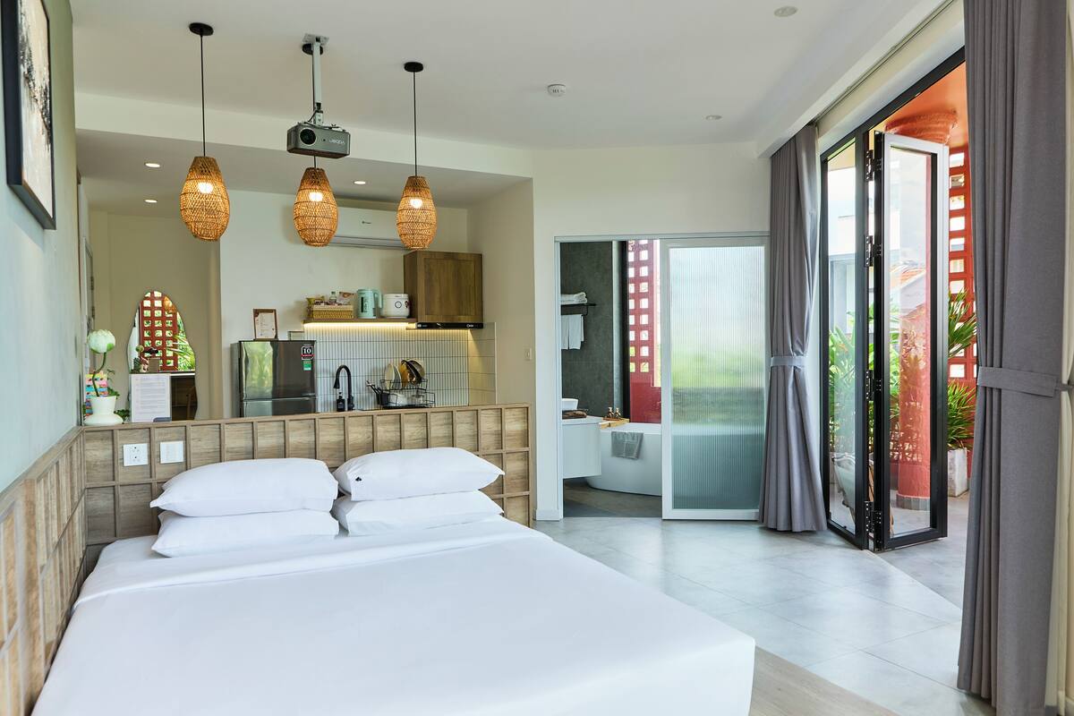 Une chambre d’hôtel moderne dotée d’un grand lit, d’une salle de bain et d’un balcon avec des rideaux.
