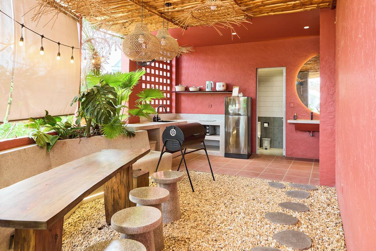 Une cuisine moderne avec un mur rouge, un banc en bois et un barbecue.