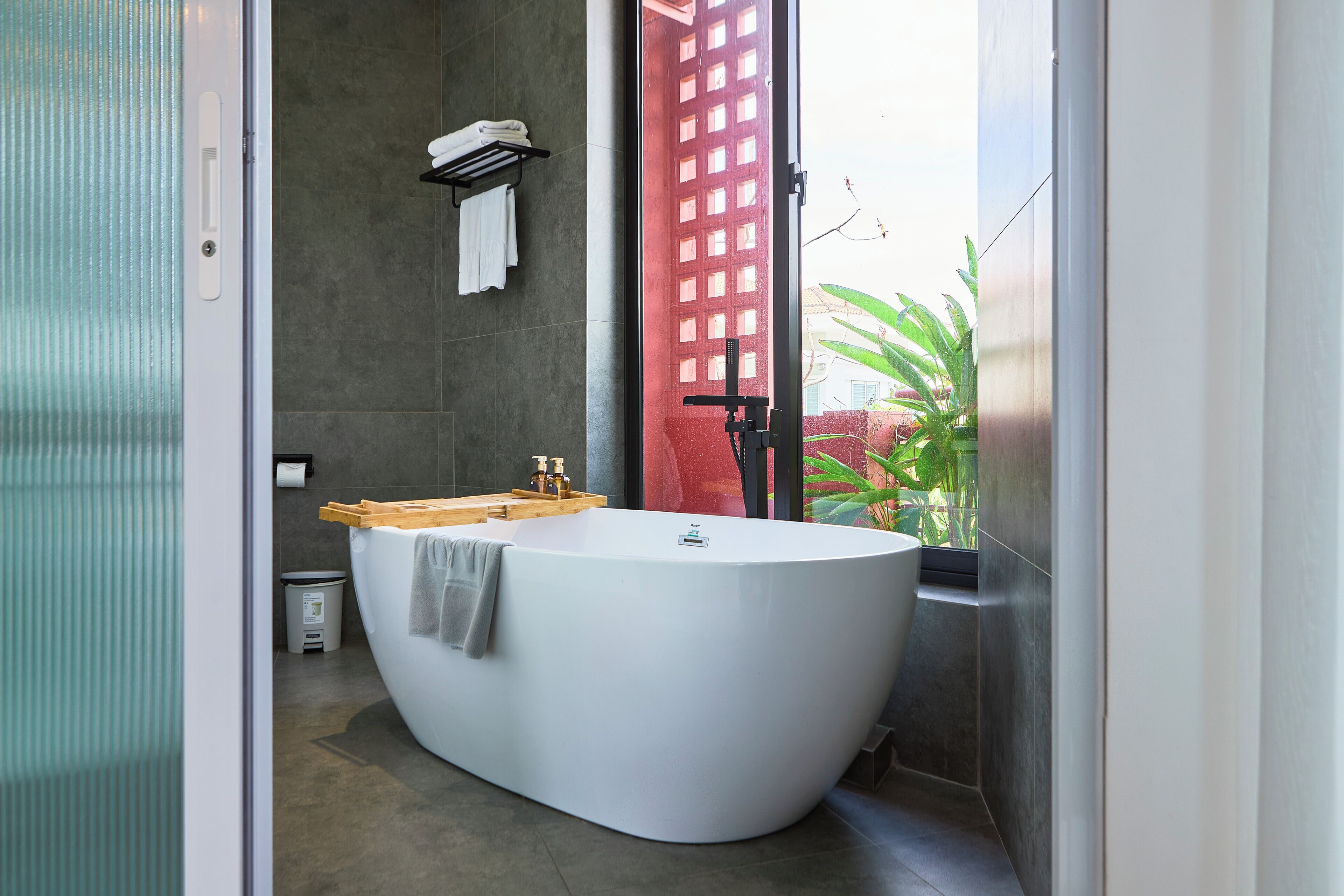 A modern bathroom with a freestanding bathtub, a wooden vanity, and a towel rack.