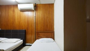 A room with two beds, wooden paneling on the walls, and an air conditioning unit mounted above the beds. - OYO 90838 Ros Heritage Motel (George Town)