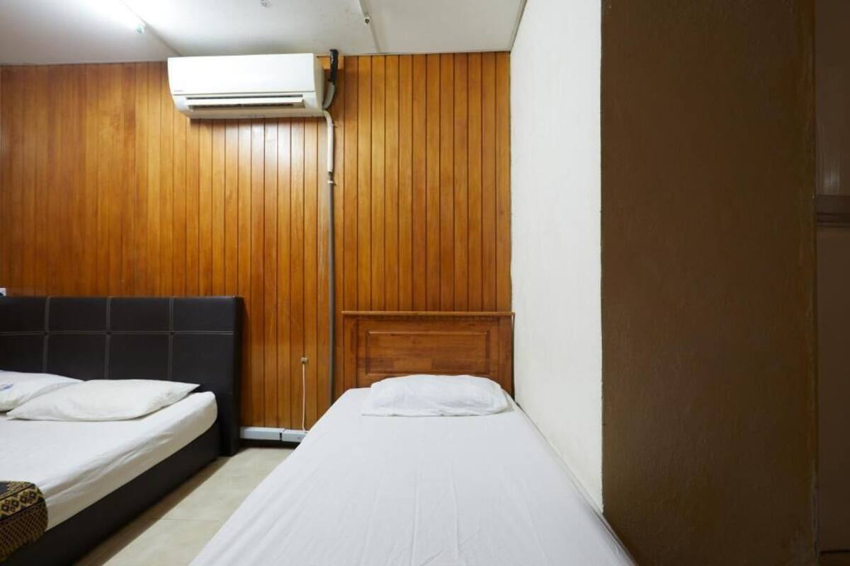 A room with two beds, wooden paneling on the walls, and an air conditioning unit mounted above the beds.