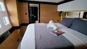 A hotel room with a large bed, a bedside table, a lamp, and a door leading to another room. - El Nido (El Nido)