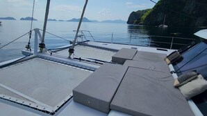 A boat deck with a seating area, a mast, and a view of the sea and distant islands. - El Nido (El Nido)