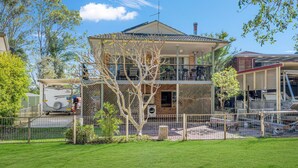 Une maison à deux étages avec un balcon, une cour clôturée et un camion garé.