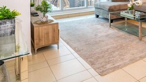 A modern living room with a glass coffee table, a beige sofa, and a dining area with a white table. - HomesGetaway-Torch Marina Dubai Cozy 2BR (Dubai)