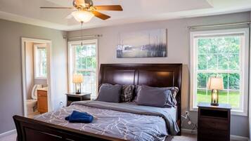 A bedroom with a bed, a ceiling fan, a window, and a nightstand.