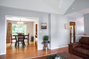 A spacious living room with a brown leather sofa, a dining area with a wooden table and chairs, and a kitchen with stainless steel appliances. - #11 - 4 Bedrooms, 3 Baths! Sleeps up to 8 (Plainville)