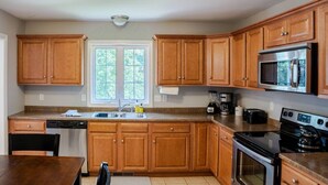 A kitchen with wooden cabinets, a stainless steel refrigerator, a stove, and a dishwasher.