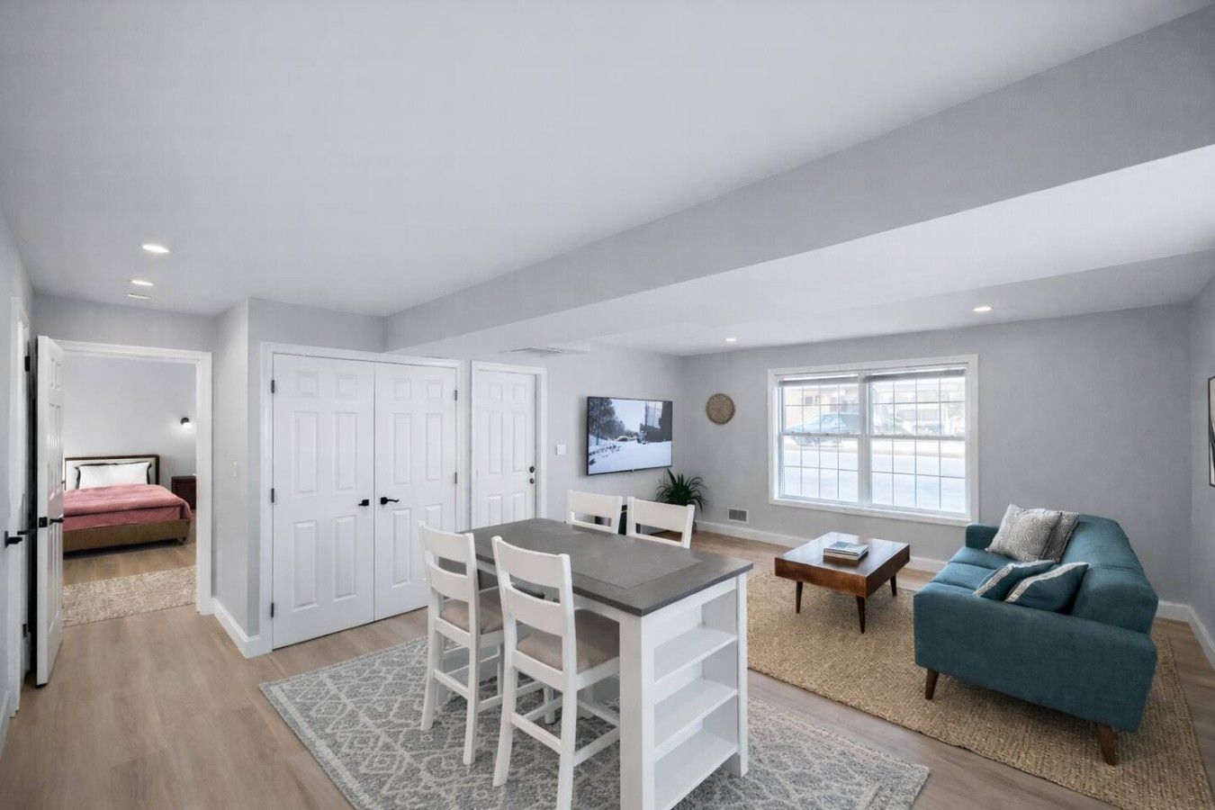 A modern living room with a dining area, a sofa, and a TV mounted on the wall.