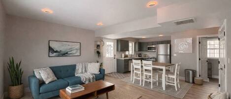 A modern living room with a sofa, coffee table, and a dining area with chairs.