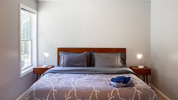 Une chambre à coucher avec un lit, deux tables de chevet et une fenêtre.