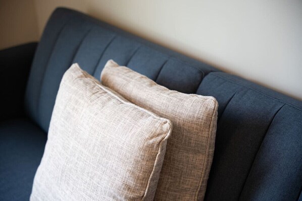 Un sofá azul oscuro con dos almohadas color beige.