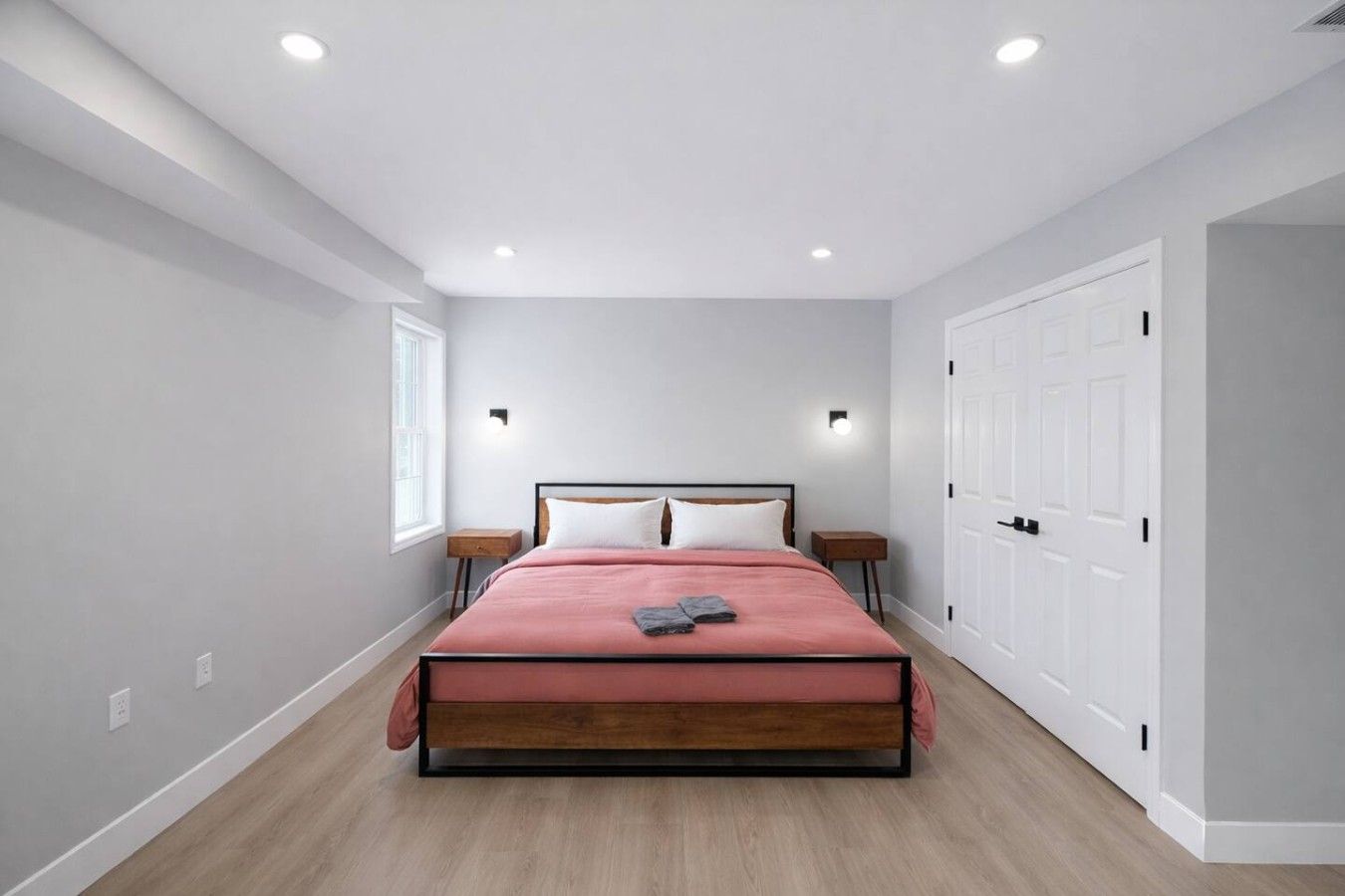Un dormitorio con cama, mesitas de noche, armario e iluminación empotrada en el techo.