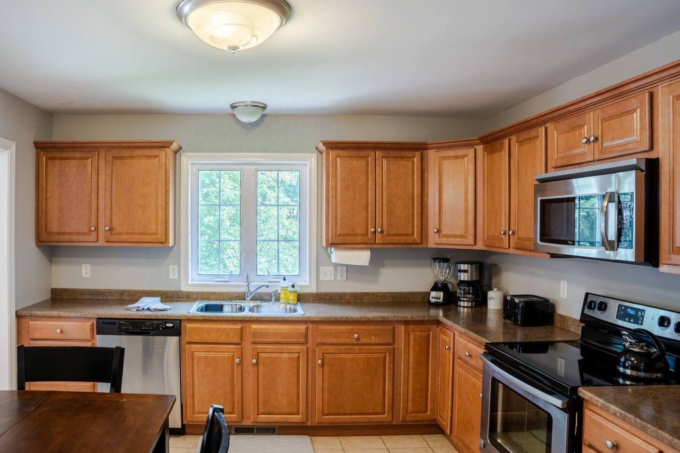 A kitchen with wooden cabinets, a microwave, a stove, and a dishwasher.