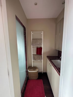 A compact bathroom with a white towel rack, a red towel, a small wicker basket, and a red mat on the floor. - Luxurious 5-bedroom Holiday House in Knokke-heist Belgique (Knokke-Heist)