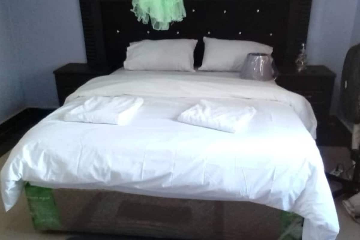A neatly made bed with white linens and two folded towels.