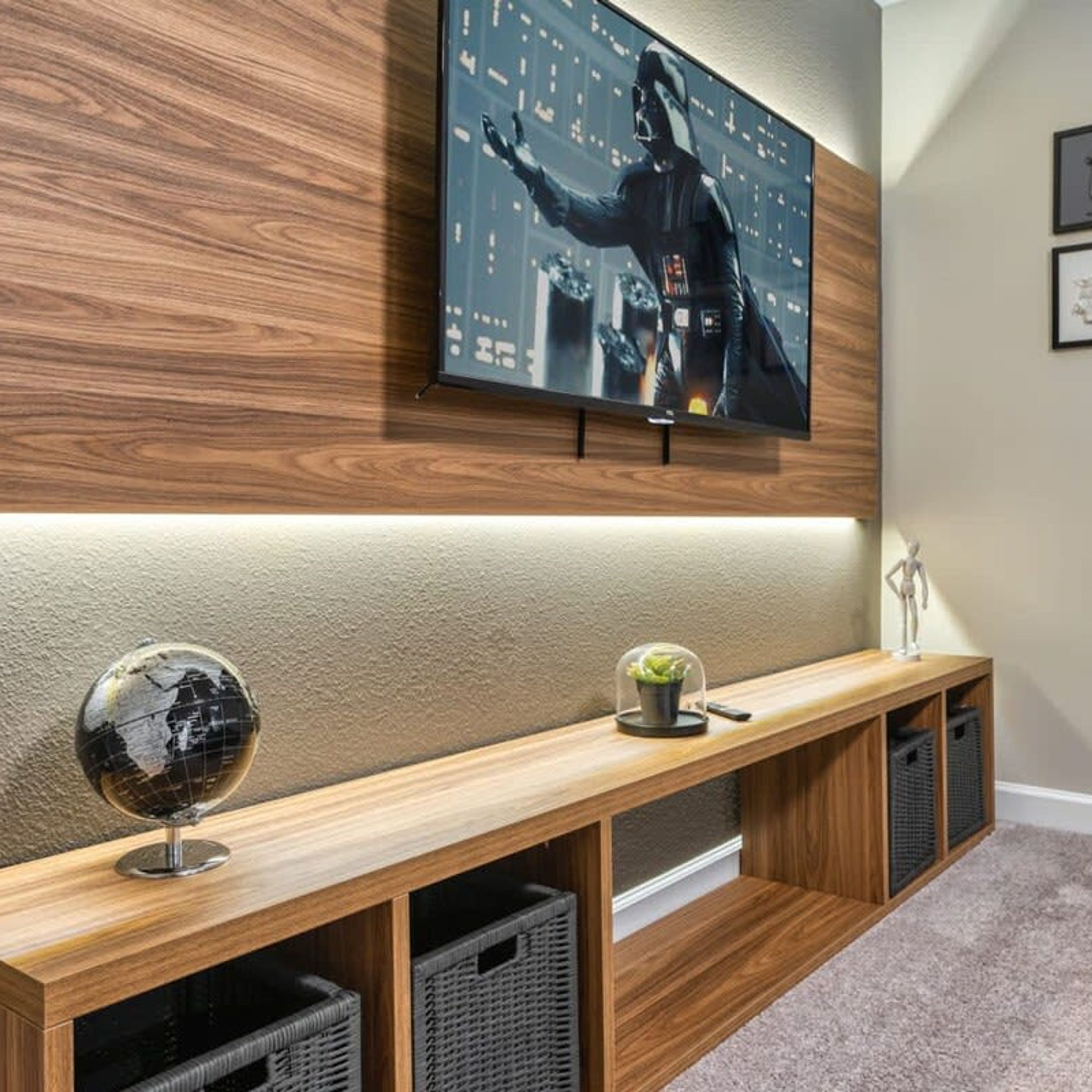 Un salon moderne avec un téléviseur à écran plat fixé à un mur en bois, un meuble de rangement en bois en dessous, et un globe sur la gauche.
