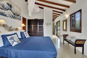 A hotel room with a large bed, a wardrobe, a bench, and a wall with artwork.