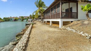 A coastal hotel with a covered outdoor area, a stone pathway, and palm trees. - Casa de las Brisas with Large Communal Pool (Kralendijk)
