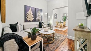 A modern living room with a sofa, coffee table, and artwork on the wall. - Spacious 3-Bed Brownstone, near Columbia Uni (New York)
