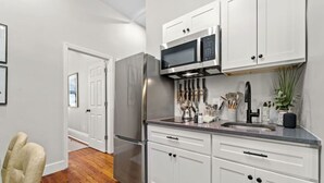 A modern kitchen with white cabinets, stainless steel appliances, and a wooden floor. - Spacious 3-Bed Brownstone, near Columbia Uni (New York)