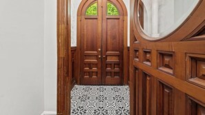 Una puerta doble de madera con un ventanal, que da a un pasillo con baldosas.